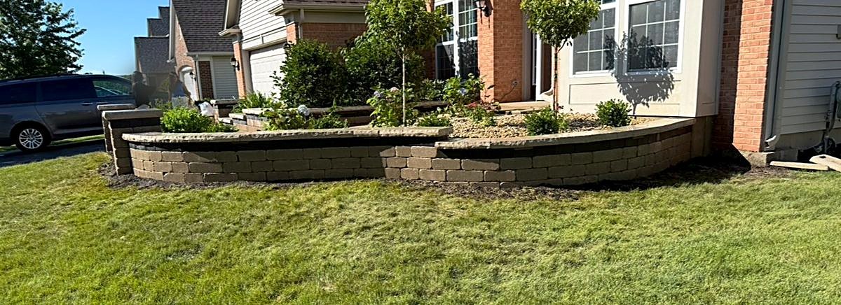 Curved block seat wall and foundation planting bed across the front of a home in Aurora, Illinois